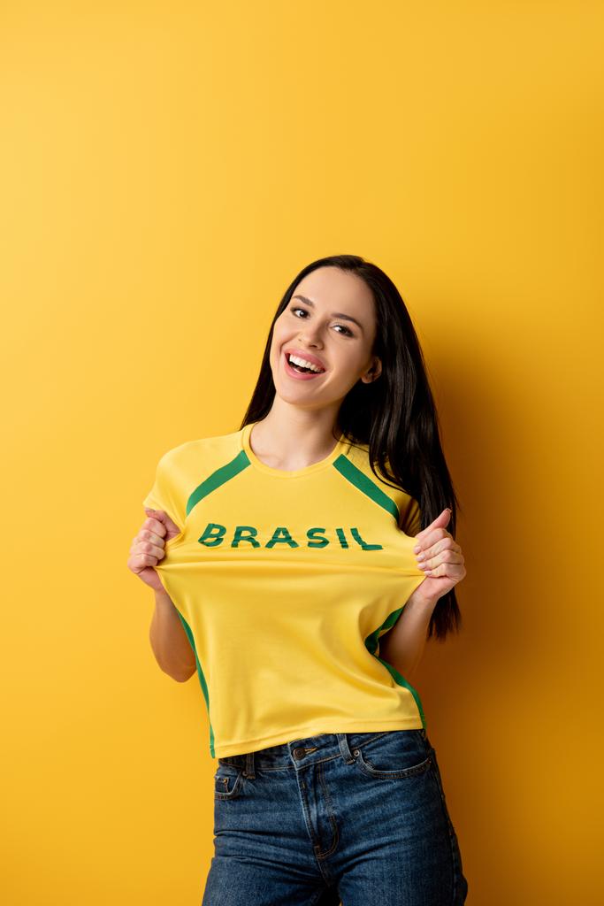 alegre abanico de fútbol femenino en camiseta amarilla con cartel brasileño en amarillo
   - Foto, imagen