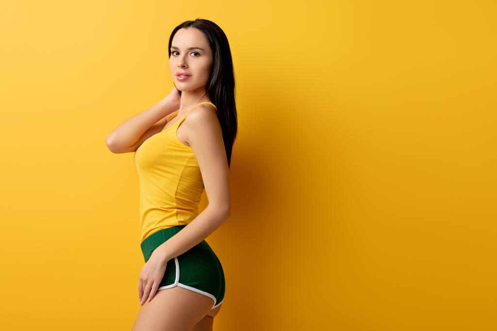 aantrekkelijk meisje staan in groen shorts op geel  - Foto, afbeelding