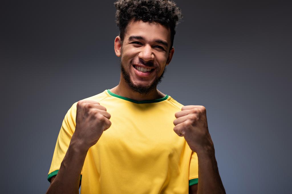 Mutlu Afro-Amerikan futbol fanatiği sarı tişörtlü, gri jestli - Fotoğraf, Görsel