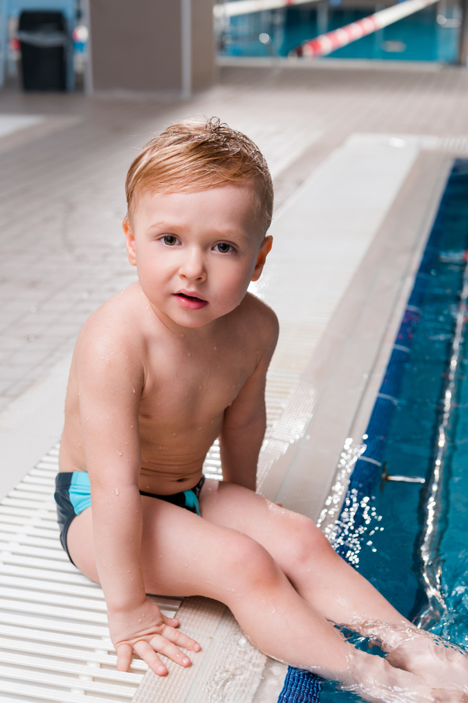 adorable toddler boy sitting near swimming pool  - Photo, Image