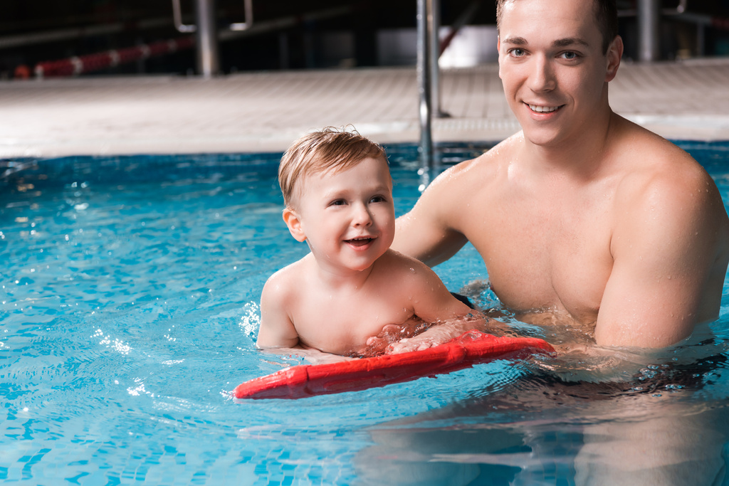 happy swim coach teaching cheerful toddler kid with flutter board in swimming pool  - Photo, Image