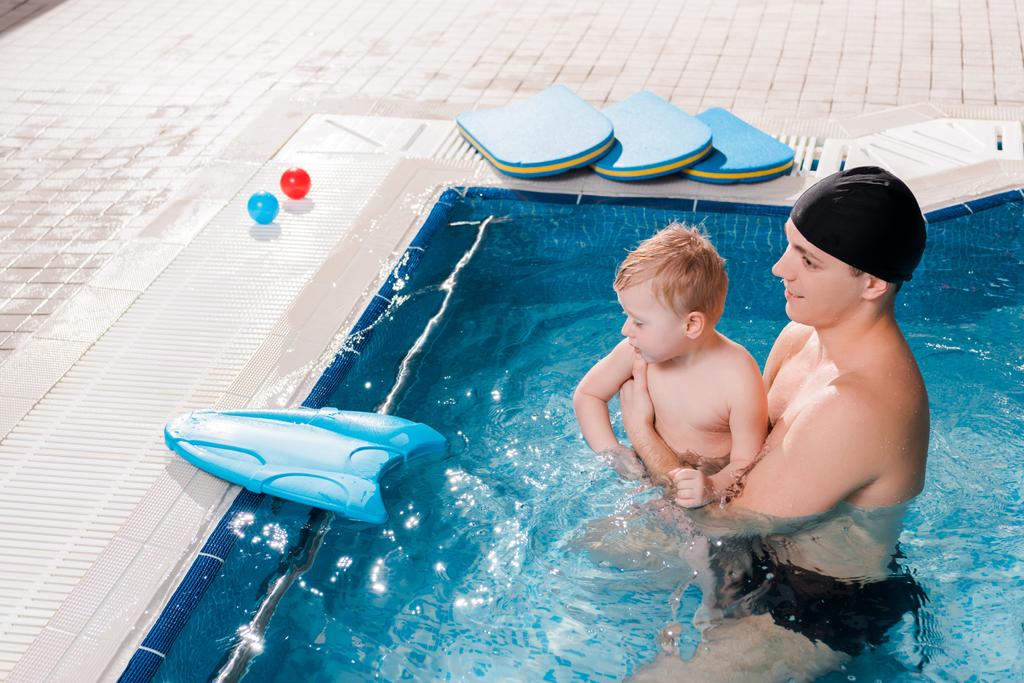 水泳プールで幼児と一緒に泳ぐコーチの明るい眺め  - 写真・画像