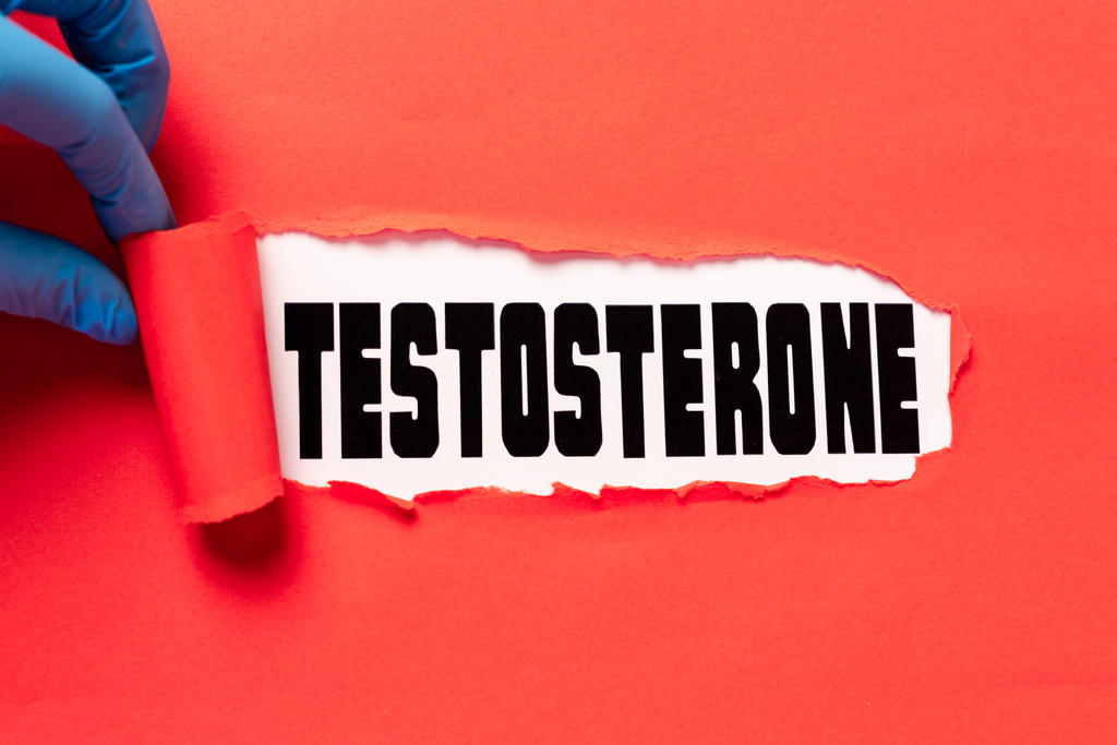 Doktorun beyaz yüzeyde testosteron harfleriyle kırmızı kağıdı yırttığı görüntüler. - Fotoğraf, Görsel