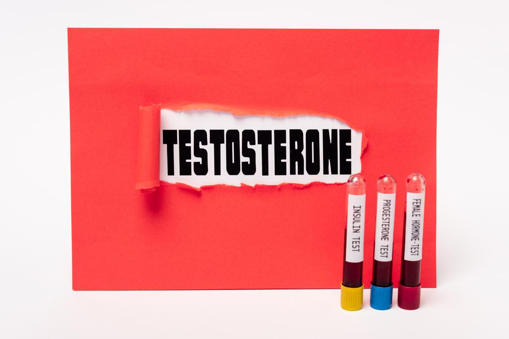 Letras de testosterona en el agujero de papel rojo y tubos de ensayo con muestras de sangre de insulina, progesterona y pruebas hormonales femeninas sobre fondo blanco
 - Foto, imagen