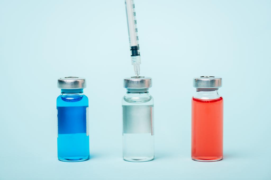 Close up view of syringe and jars of hormonal drugs on blue surface - Photo, Image