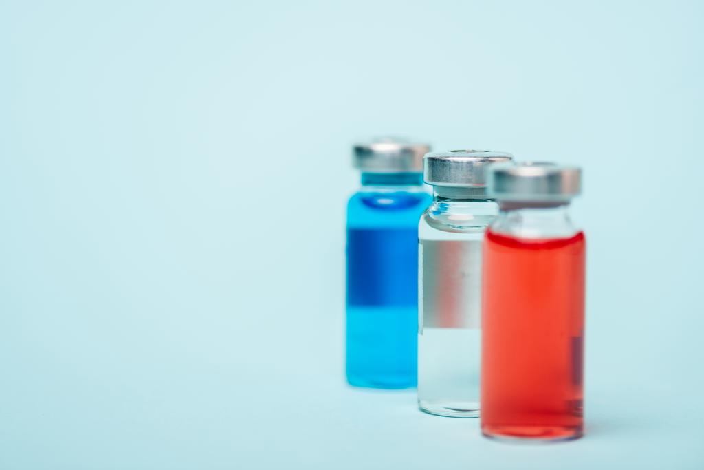 Foco seletivo de três jarros de drogas hormonais na superfície azul
 - Foto, Imagem