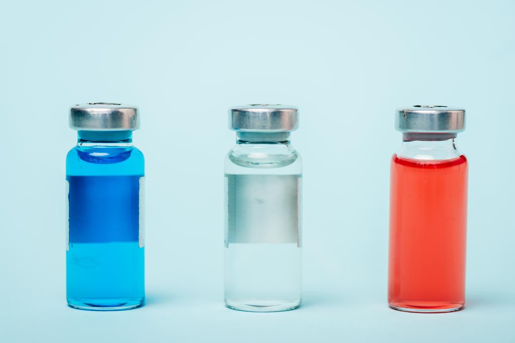 Vista de cerca de frascos de colores con medicamentos hormonales en la superficie azul
 - Foto, imagen