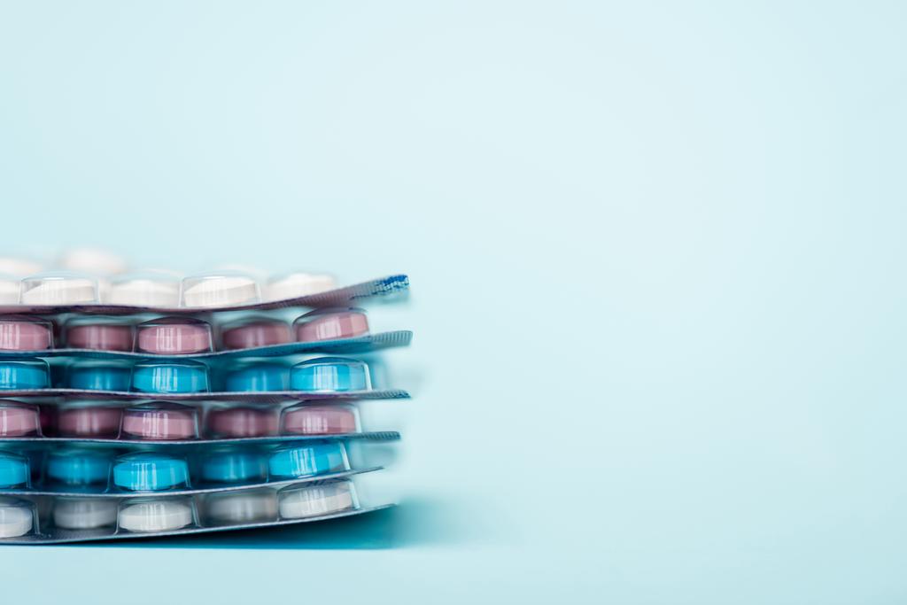 Vista de cerca de las ampollas apiladas con píldoras hormonales en la superficie azul con espacio de copia
 - Foto, Imagen