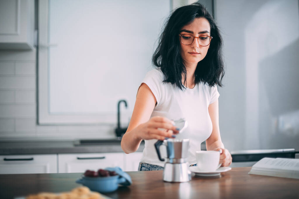 Piękna młoda kobieta nalewająca kawę do kuchni - Zdjęcie, obraz