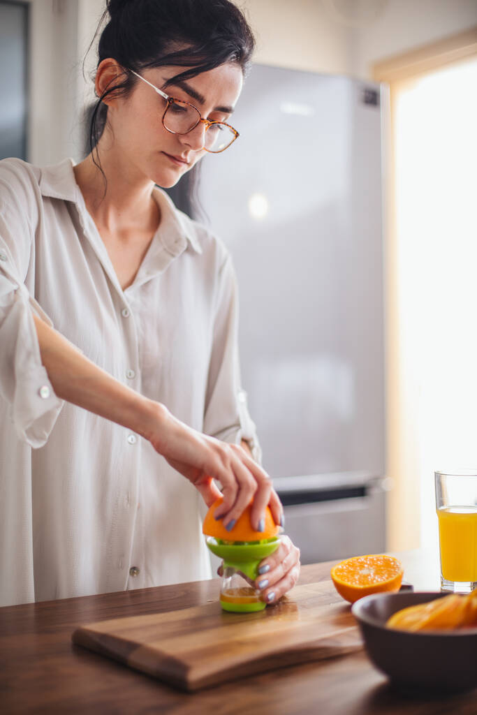 Γυναίκα κάνει χυμό πορτοκαλιού στην κουζίνα - Φωτογραφία, εικόνα