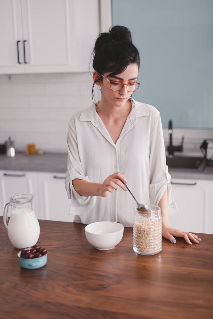 Kaunis nuori nainen tekee aamiaista keittiössä
 - Valokuva, kuva