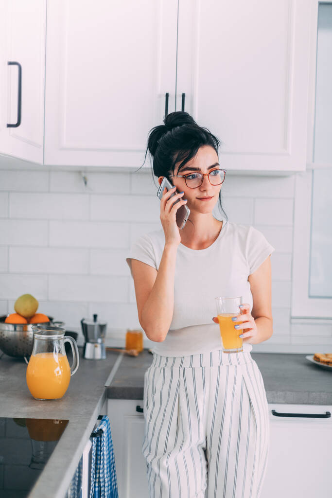 Hermosa joven hablando en un teléfono celular en la cocina
 - Foto, imagen