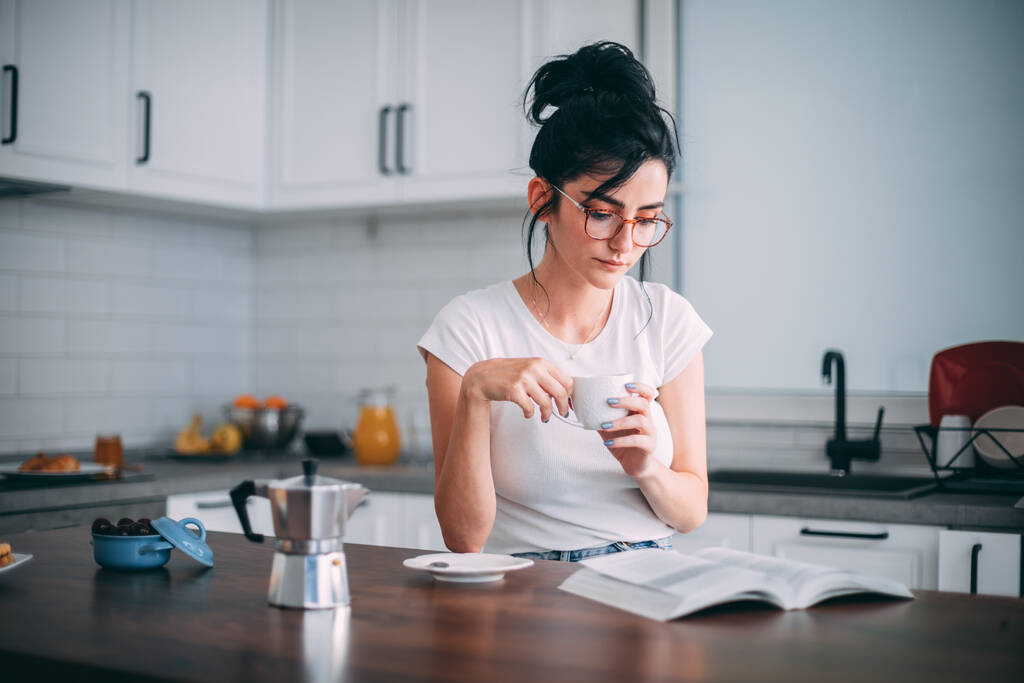Schöne junge Frau liest Buch in der Küche - Foto, Bild