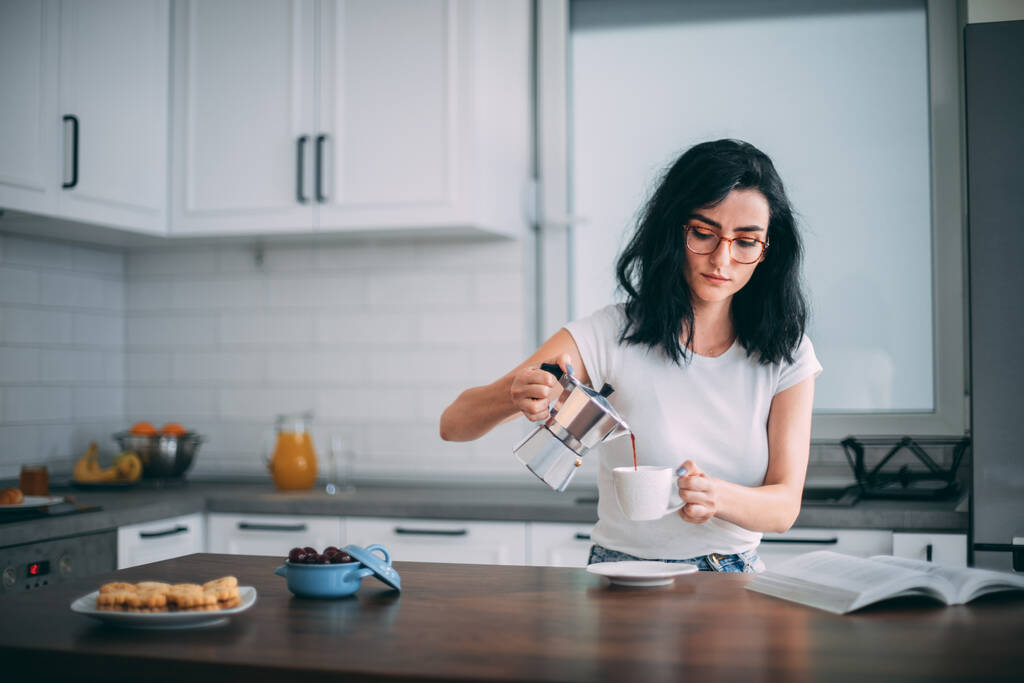 Mulher bonita derramando café na cozinha
 - Foto, Imagem