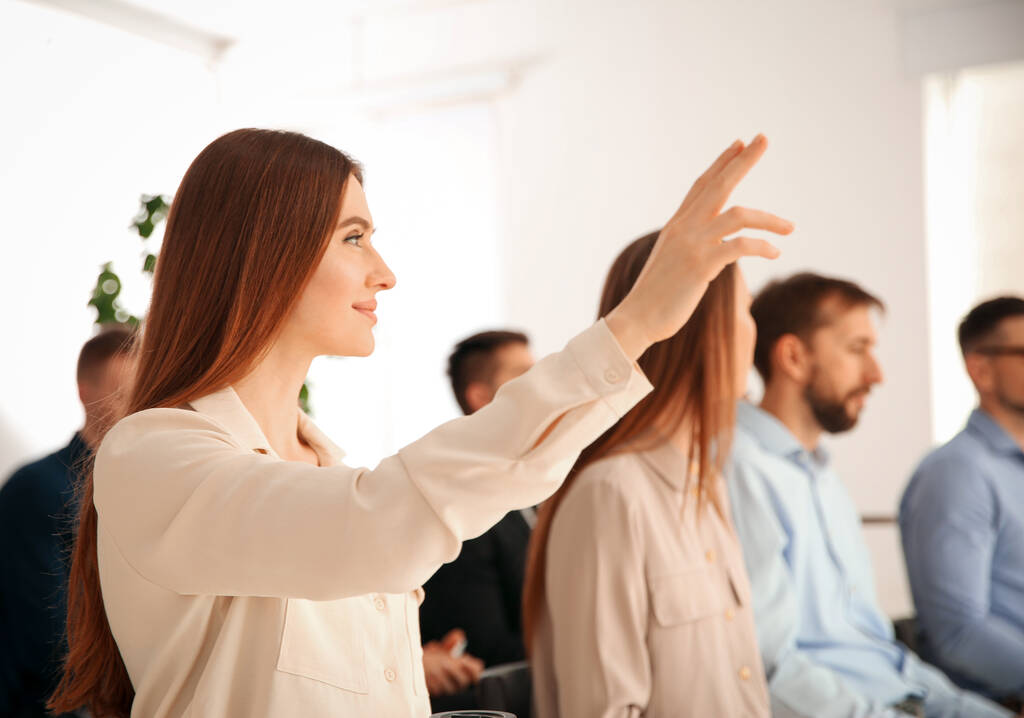 Kobieta podnosząca rękę zadać pytanie na szkoleniu biznesowym w pomieszczeniach - Zdjęcie, obraz