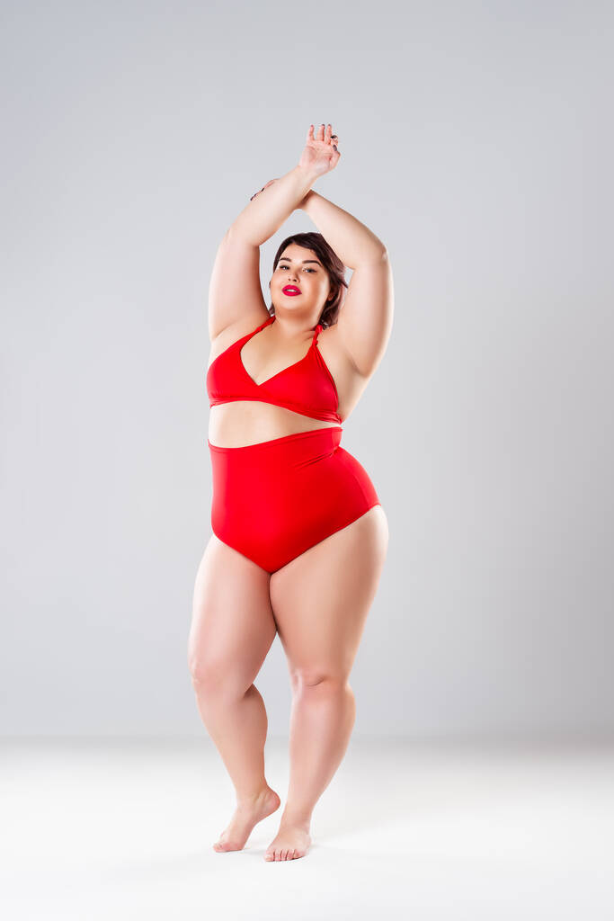 Συν μέγεθος μοντέλο μόδας σε κόκκινο μαγιό, χοντρή γυναίκα σε εσώρουχα σε γκρι φόντο, το σώμα θετική έννοια - Φωτογραφία, εικόνα