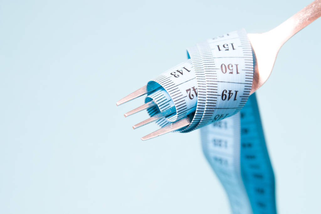 cinta métrica azul en un tenedor como una pasta sobre un fondo azul concepto de dieta ayuno pérdida de peso y pérdida de peso
 - Foto, imagen