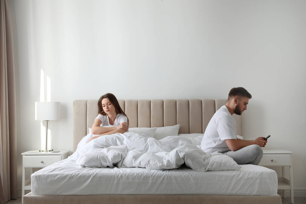 Jeune homme préférant smartphone sur sa petite amie sur le lit à la maison. Problèmes relationnels
 - Photo, image