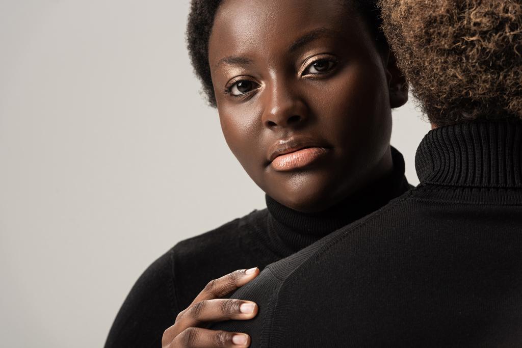 afro-americana donne in nero dolcevita abbracci isolato su grigio
 - Foto, immagini
