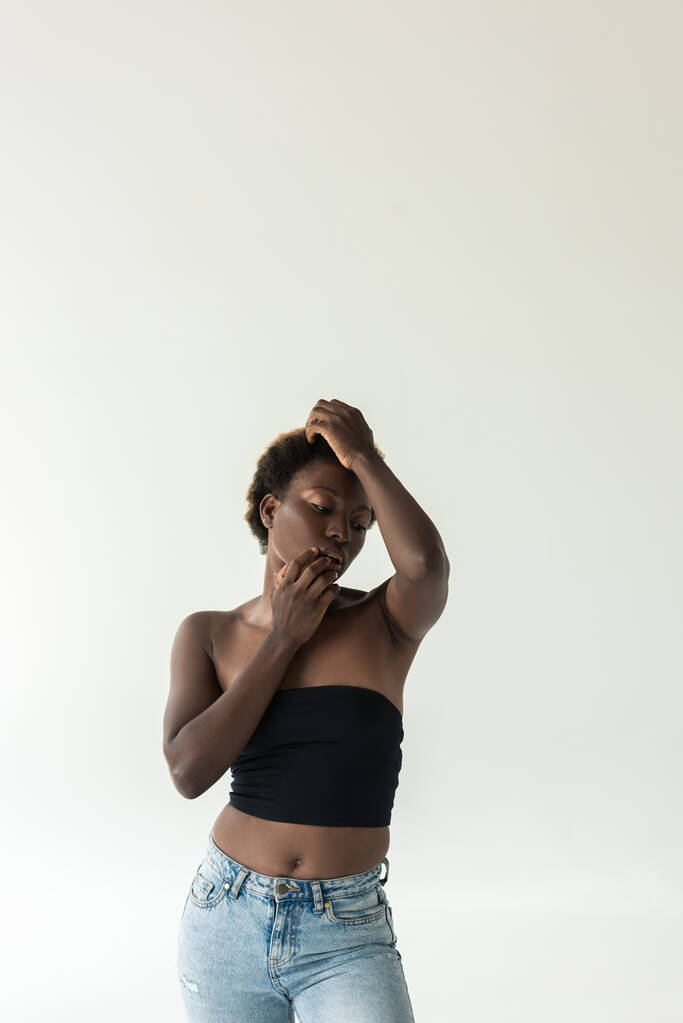 przetargu afrykański amerykański dziewczyna w dżinsy i czarny top izolowane na szary - Zdjęcie, obraz