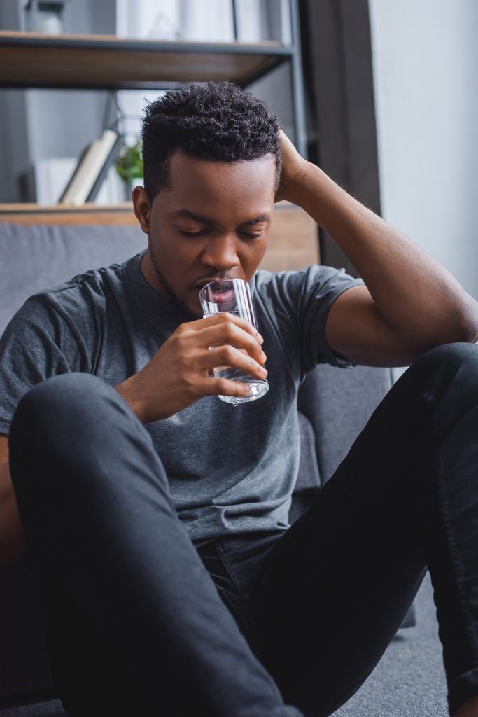 στρεσαρισμένος μοναχικός Αφροαμερικάνος που πίνει νερό στο σπίτι - Φωτογραφία, εικόνα