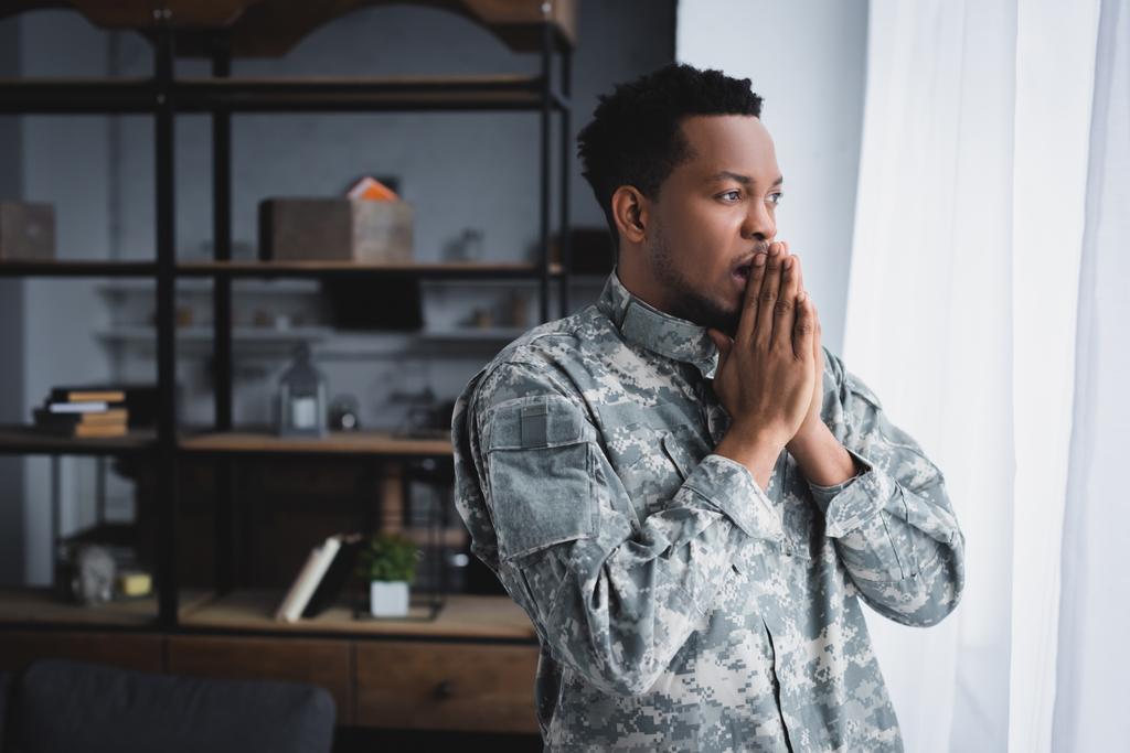 Soldado afroamericano preocupado en uniforme militar en casa
 - Foto, imagen