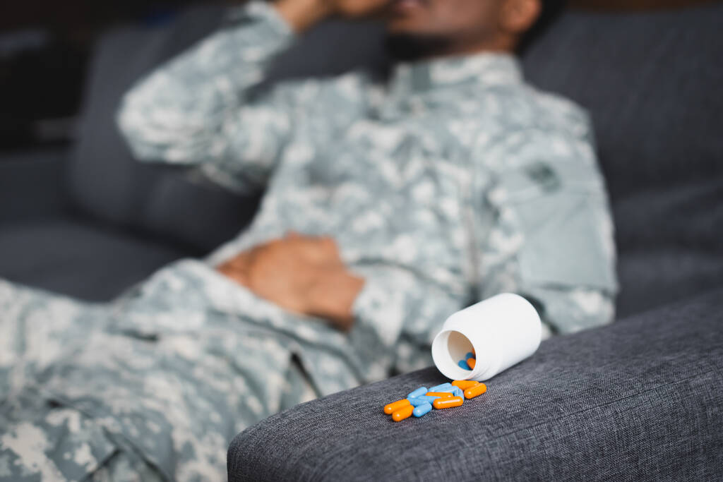 selektiver Fokus auf Pillen und müde afrikanisch-amerikanische Soldaten, die zu Hause an PTBS leiden, abgeschnittene Ansicht - Foto, Bild