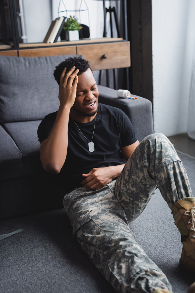 płaczący afrykański żołnierz z odznaką wojskową cierpiący na PTSD w domu - Zdjęcie, obraz