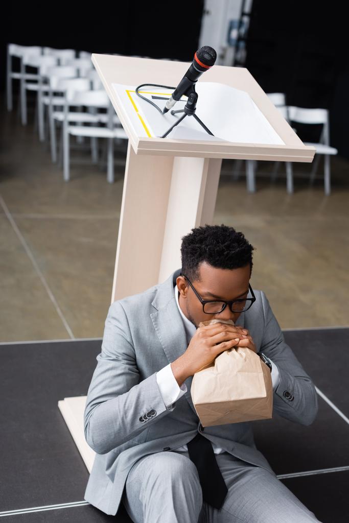 Ödlek Afro-Amerikan konuşmacı kağıt torbayla nefes alıp veriyor ve iş konferansından önce panik atak geçiriyor.  - Fotoğraf, Görsel