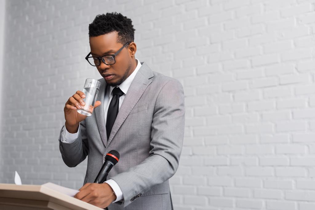 nervoso afro-americano empresário beber água em conferência de negócios no escritório
  - Foto, Imagem