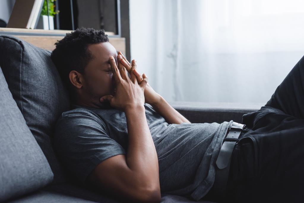 homem afro-americano estressado sentado no sofá em casa
 - Foto, Imagem