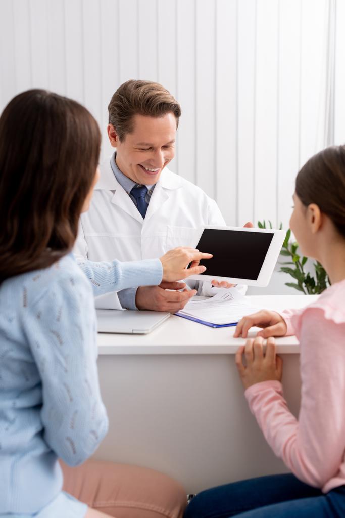 vue arrière de la mère et de la fille près du médecin montrant la tablette numérique avec écran blanc
 - Photo, image