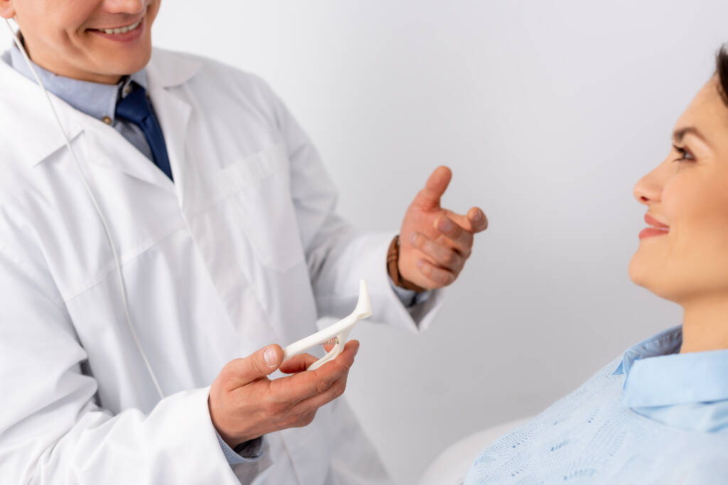 vista ritagliata del medico sorridente ent tenendo speculum nasale vicino paziente attraente
 - Foto, immagini