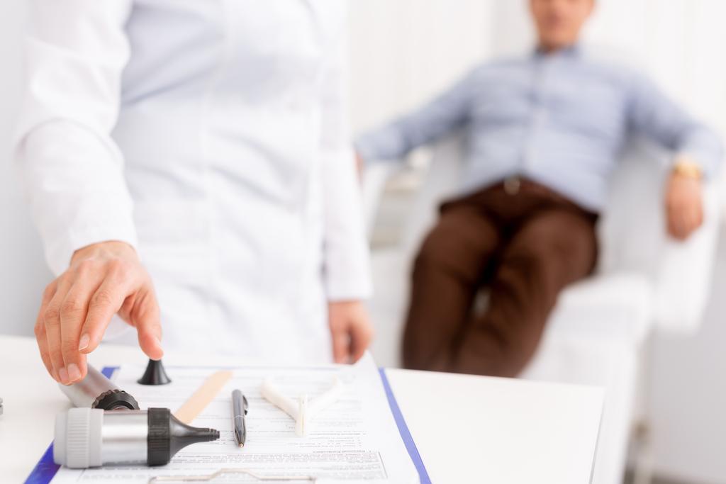 selektivní zaměření lékaře užívající otoskop a pacienta sedícího v lékařském křesle na pozadí - Fotografie, Obrázek