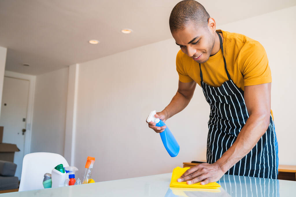 Close up de homem latino jovem limpeza manchas fora da mesa em casa. Conceito de limpeza e limpeza. - Foto, Imagem