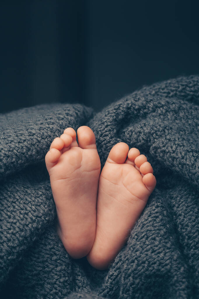 Weiche Babyfüße gegen eine dunkelgraue Decke, Nahaufnahme. Raum für Text - Foto, Bild