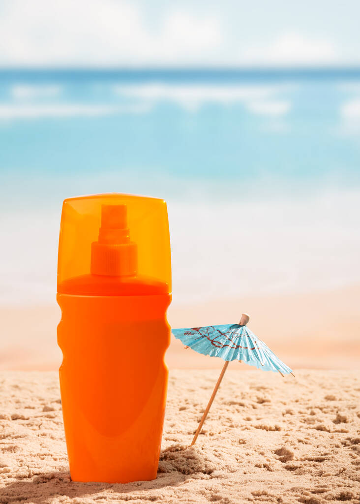 Sluneční krém a deštník v písku proti moři. - Fotografie, Obrázek