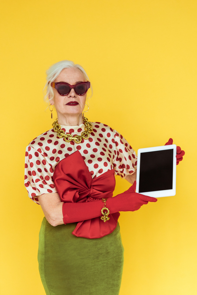 Stílusos idős nő kezében digitális tabletta izolált sárga - Fotó, kép