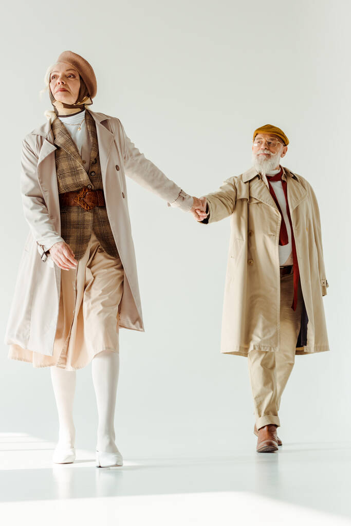 Full length of stylish senior woman holding hand of handsome man on white background - Photo, Image