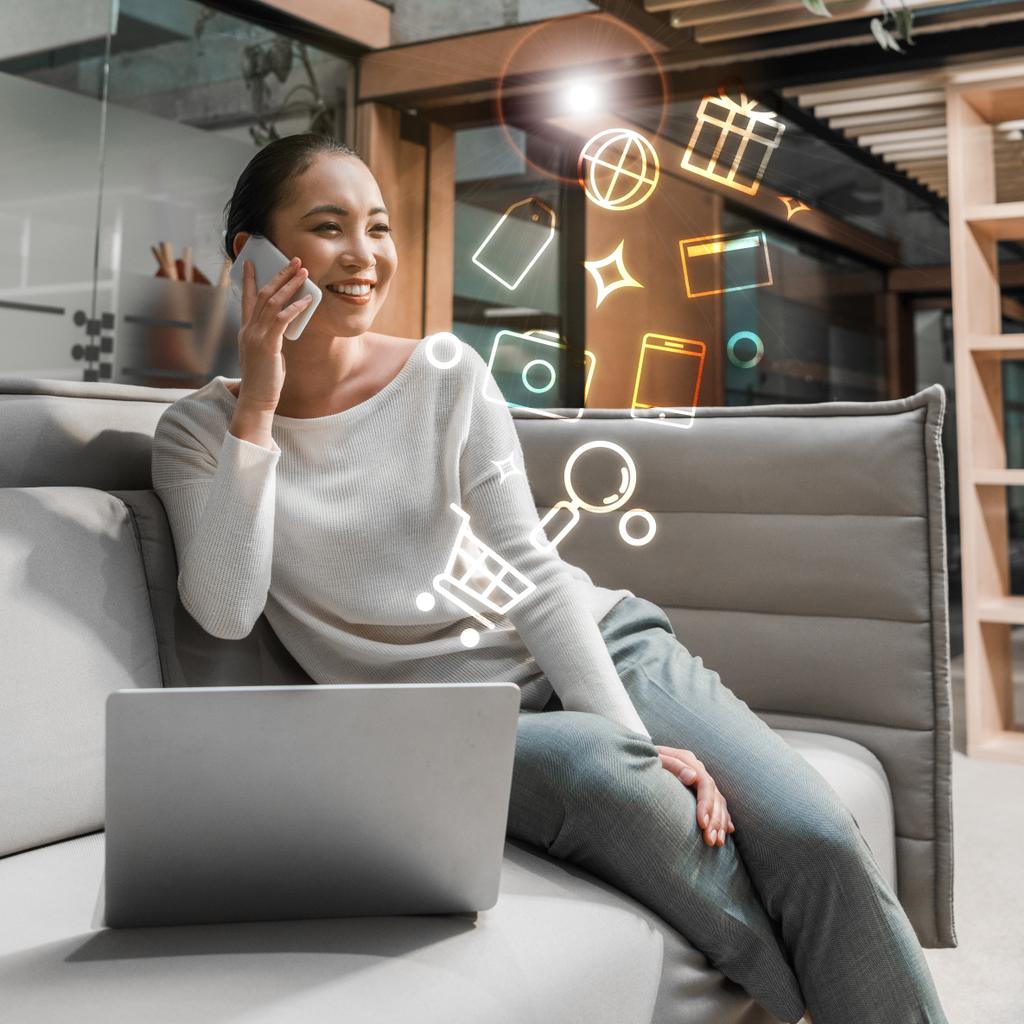 vrolijk aziatische zakenvrouw praten op smartphone terwijl zitten op de bank in de buurt van laptop, digitale pictogrammen illustratie - Foto, afbeelding