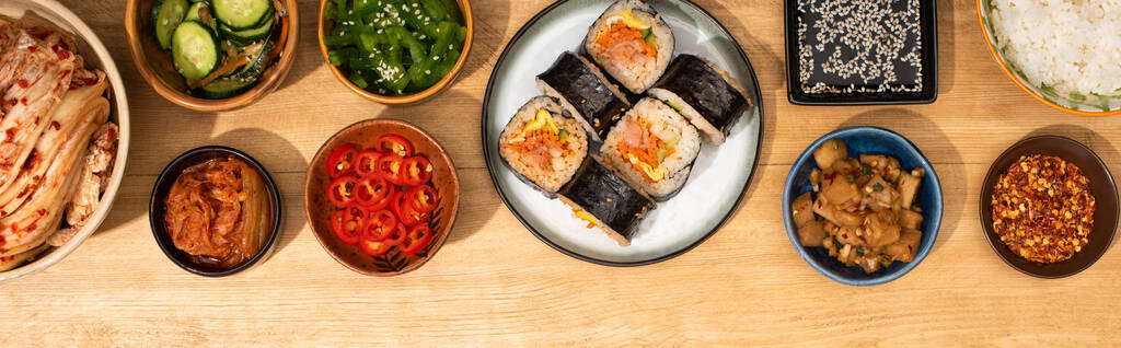 皿の上のジンバップの近くに韓国料理のサイドディッシュとボウルのパノラマショット  - 写真・画像