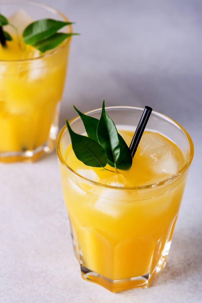 Smakelijk en verfrissend sinaasappelsap in glas met zwarte rietjes op lichtgrijze achtergrond Fris gerijpte sinaasappels - Foto, afbeelding