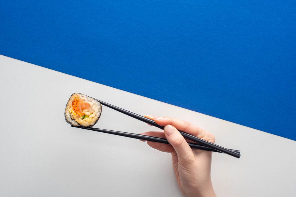 rajattu näkymä nainen tilalla syömäpuikot Korean gimbap valkoinen ja sininen
  - Valokuva, kuva