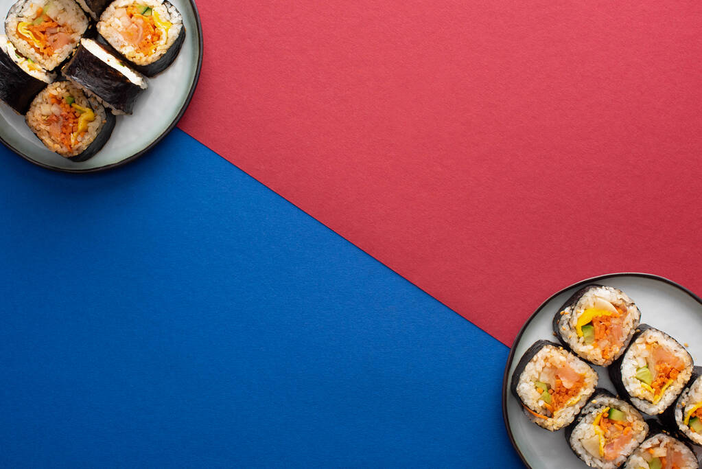 top view of plates with gimbap on crimson and blue  - Photo, Image
