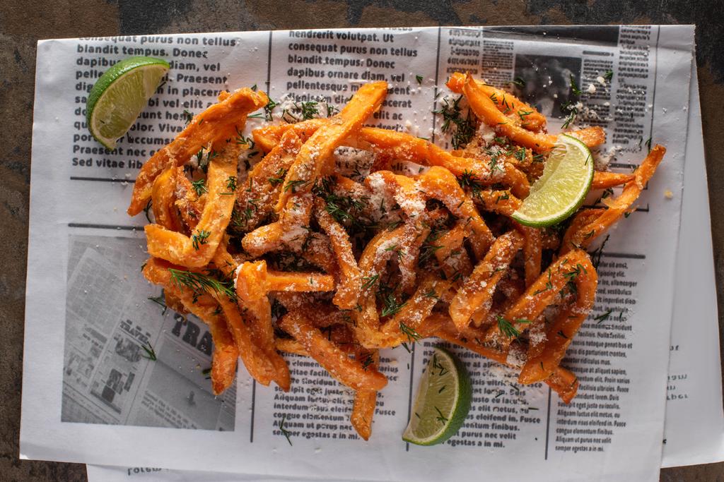 vista superior de papas fritas saladas y lima en rodajas en el periódico con texto
  - Foto, imagen