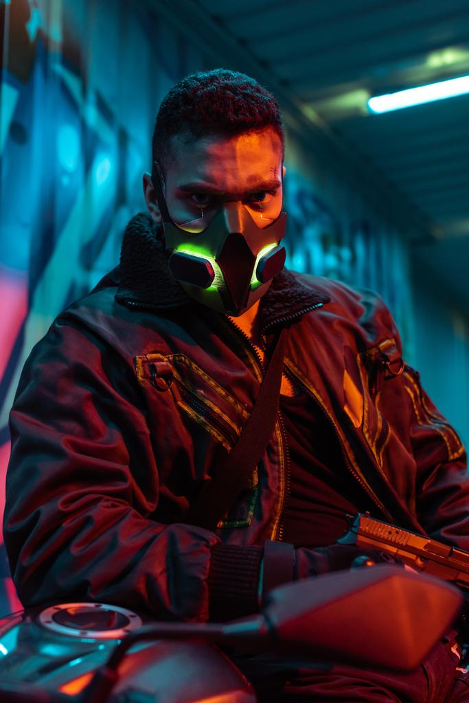 selective focus of armed mixed race cyberpunk player in protective mask - Photo, Image