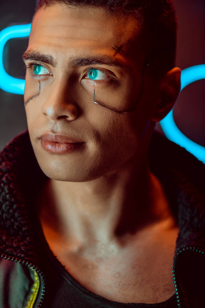 bonito e bi-racial jogador cyberpunk olhando para longe perto de neon iluminação
  - Foto, Imagem