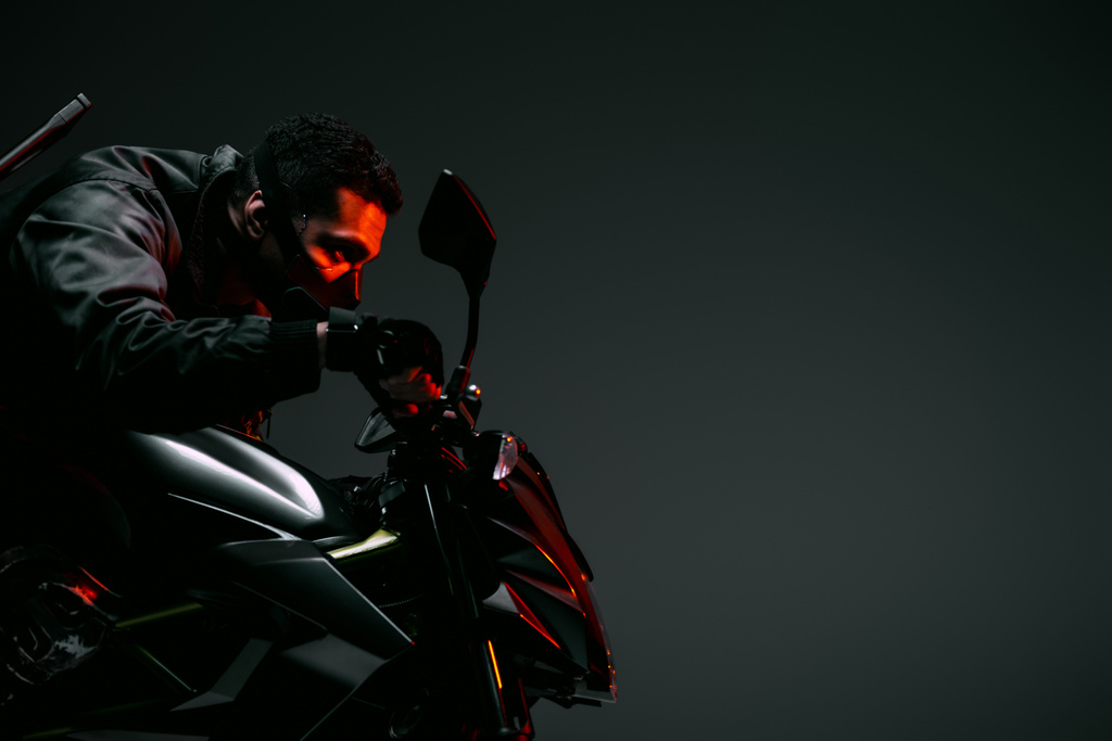 vista lateral del peligroso jugador bi-racial cyberpunk en la máscara de conducción de la motocicleta en gris
  - Foto, Imagen