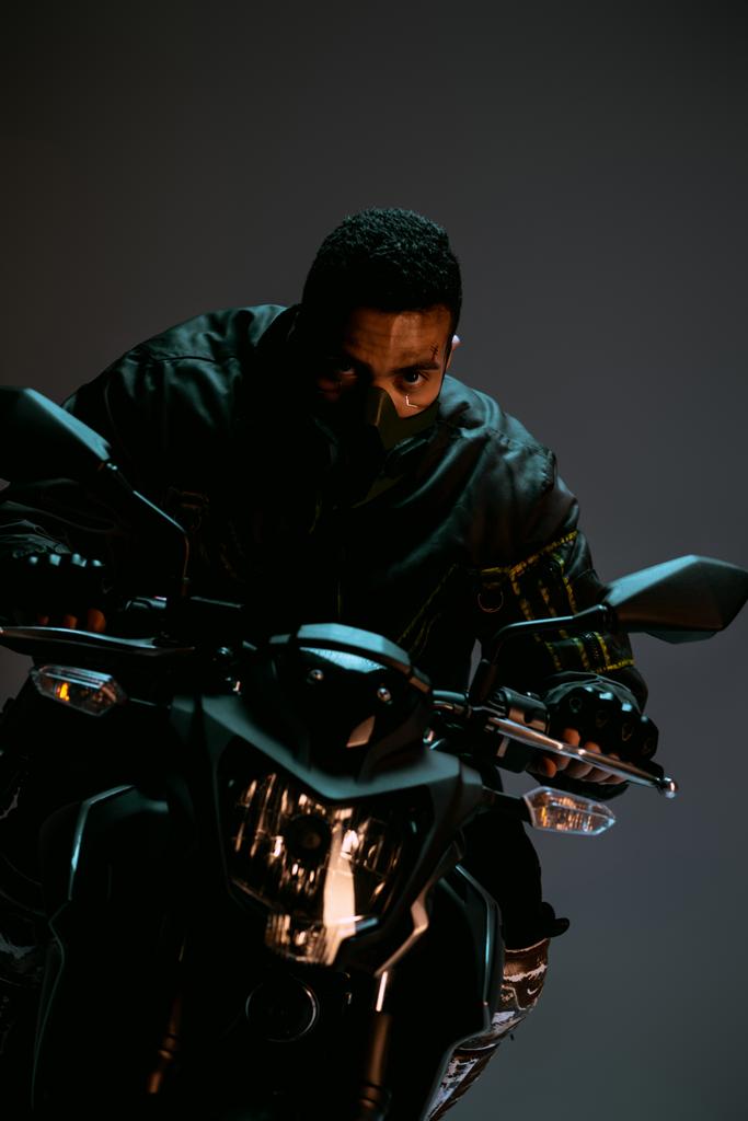 przystojny mieszane wyścig cyberpunk gracz w maska jazda motocykl na szary  - Zdjęcie, obraz