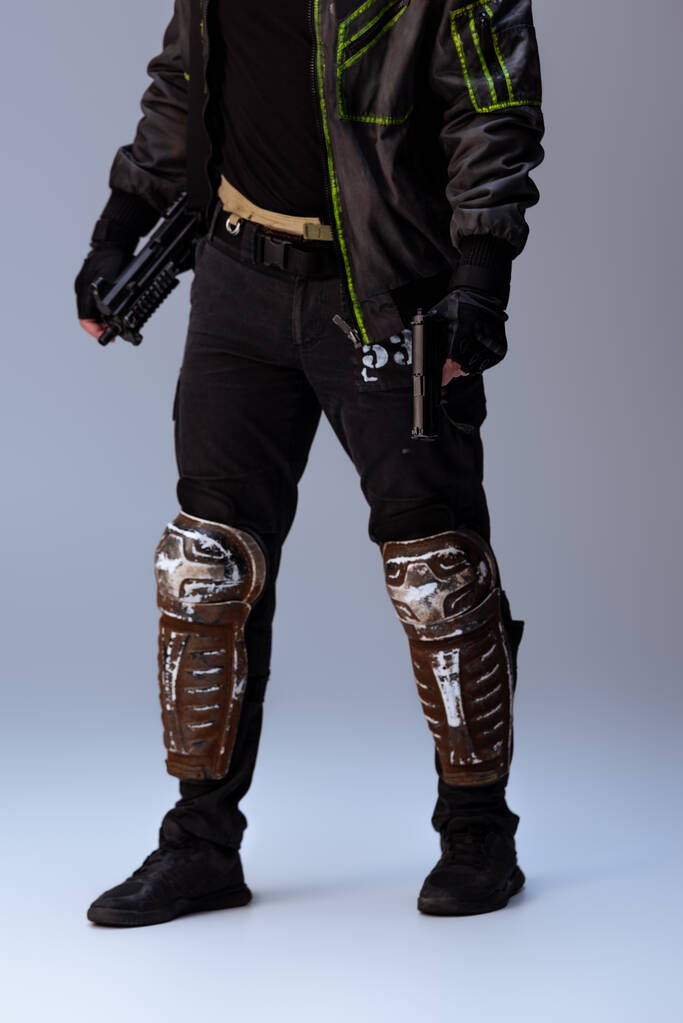 cropped άποψη του cyberpunk παίκτης κρατώντας όπλο, ενώ στέκεται σε γκρι   - Φωτογραφία, εικόνα